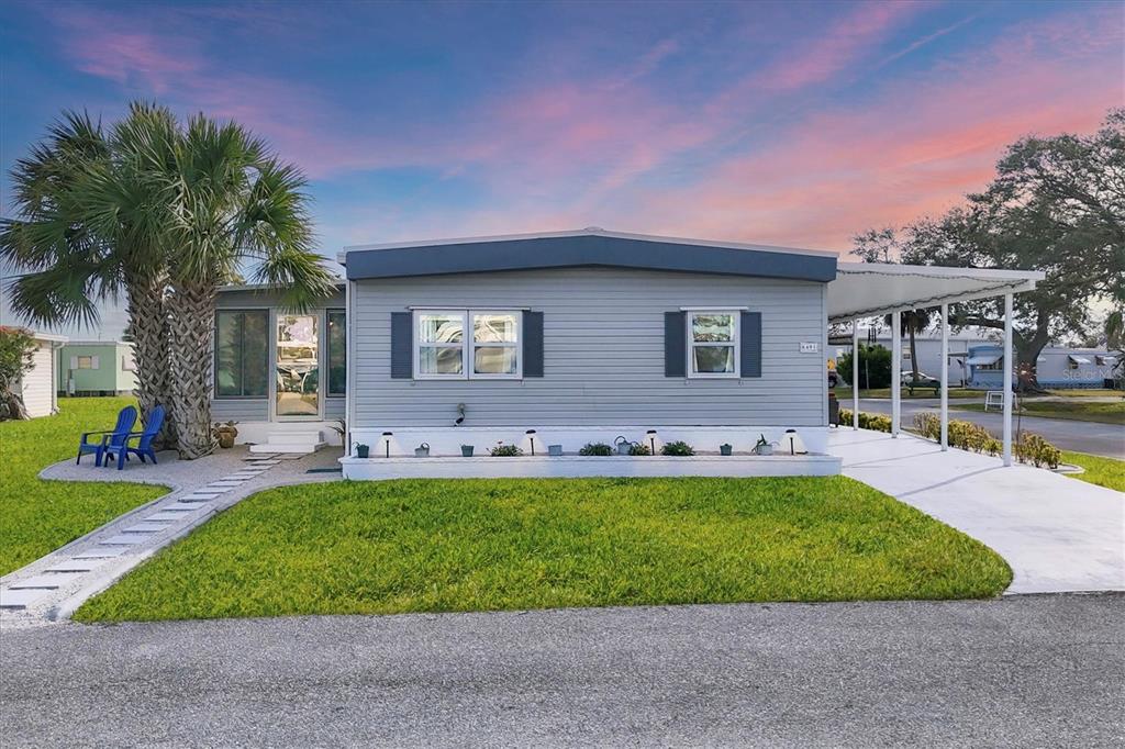 A single-story manufactured home with grey siding, a palm tree, and a covered carport — 6401 FLORAL COURT, NORTH PORT, FL