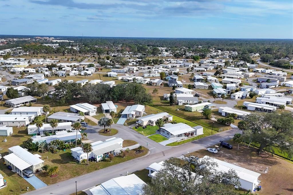 An aerial view shows a dense neighborhood of manufactured homes with paved streets and trees — 6401 FLORAL COURT, NORTH PORT, FL