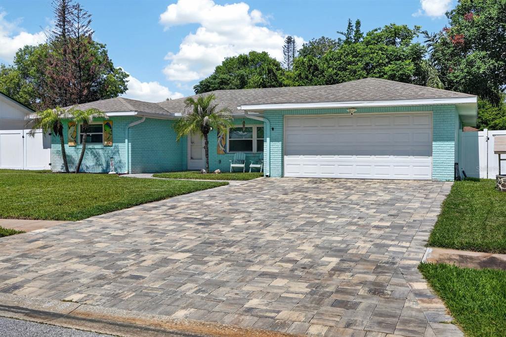 A single-story house with light blue brick siding, a paver driveway, and a two-car garage — 68 RAINTREE DRIVE, PORT ORANGE, FL