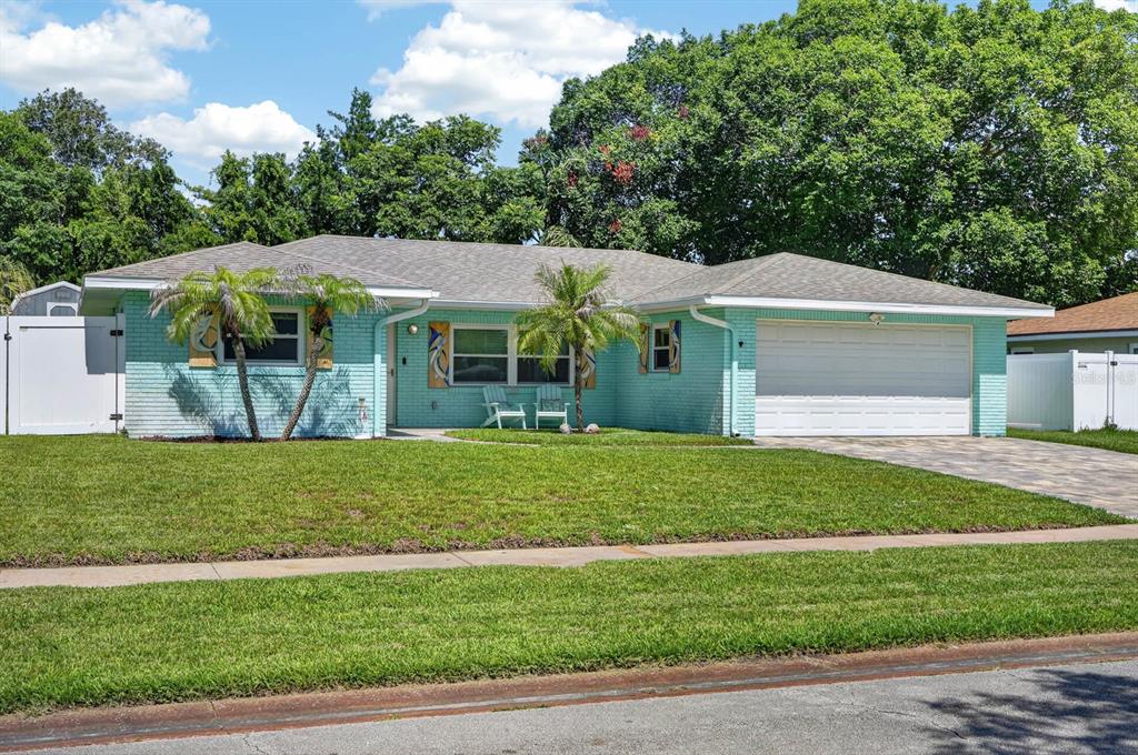 A single-story light blue brick house with a two-car garage and a front lawn — 68 RAINTREE DRIVE, PORT ORANGE, FL