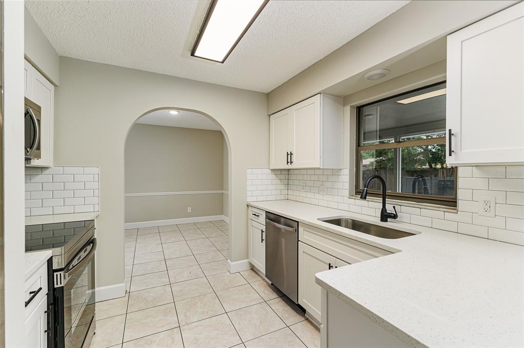 A living room features gray carpet, two armchairs by a window, and an arched doorway — 4052 LEHMAN COURT, LAKELAND, FL