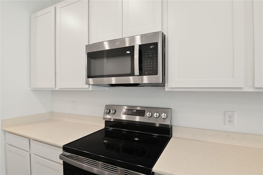 A kitchen features white cabinets, stainless steel appliances, and light-colored countertops — 5135 KINSLEY DRIVE, WINTER HAVEN, FL
