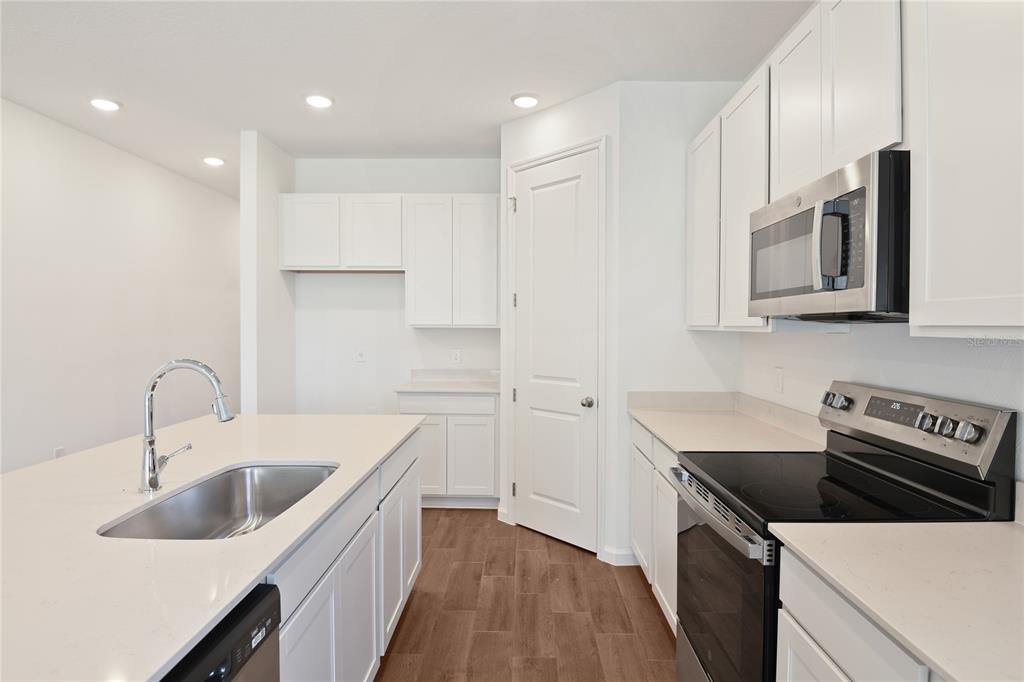 A kitchen with white cabinets, stainless steel appliances, a center island, and wood-look tile flooring — 5135 KINSLEY DRIVE, WINTER HAVEN, FL