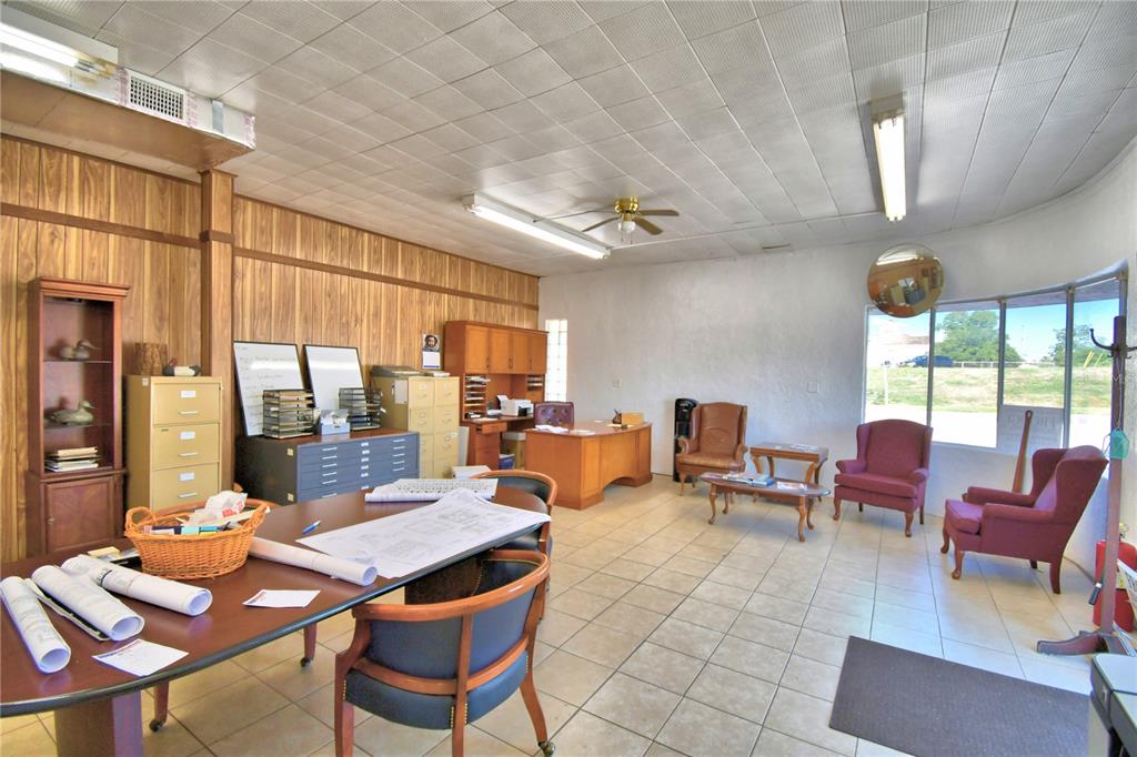 An office space features wood-paneled walls, a tiled floor, a conference table, and seating area — 105 S SCENIC HIGHWAY, FROSTPROOF, FL
