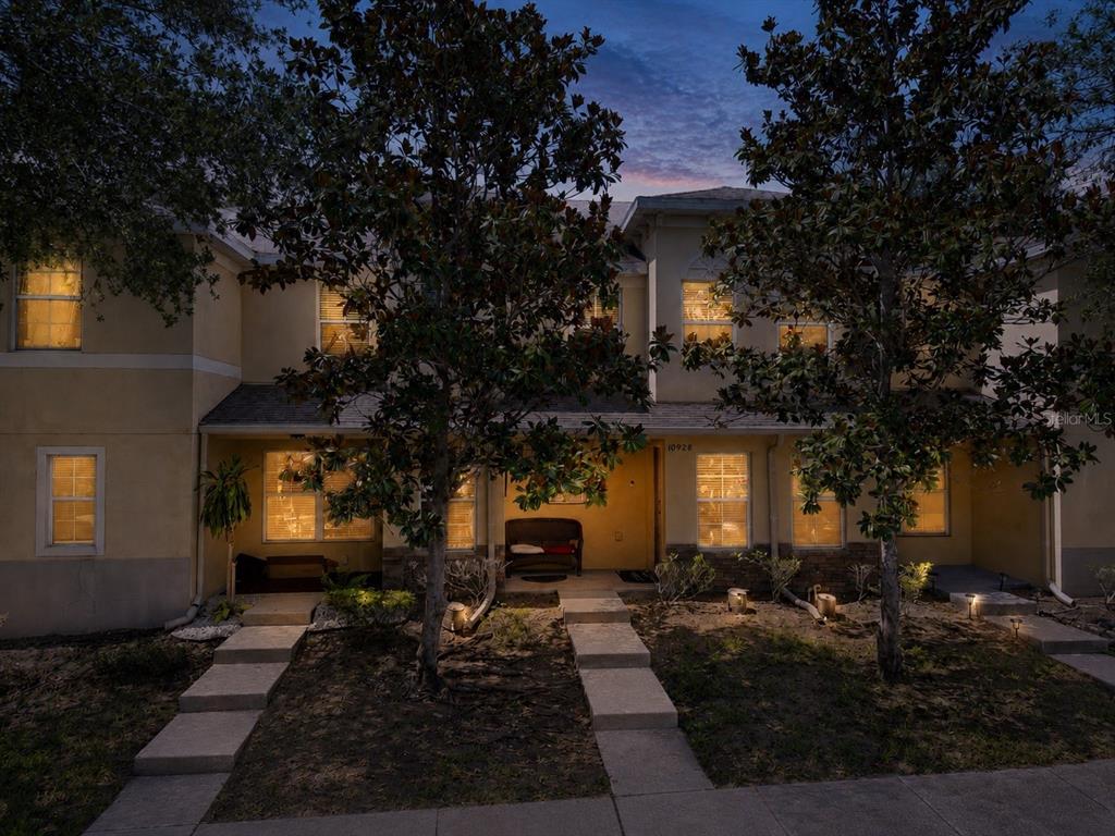 A two-story townhouse exterior at dusk with two front walkways and mature trees — 10928 KEYS GATE DR, RIVERVIEW, FL