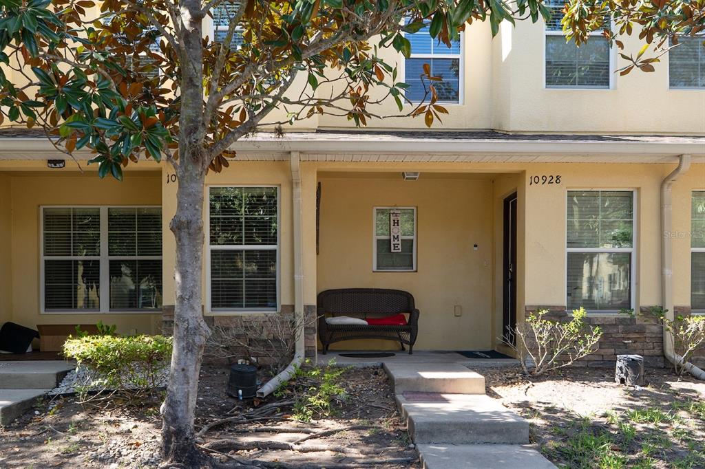 The exterior of a two-story townhouse features a covered front porch with a bench — 10928 KEYS GATE DR, RIVERVIEW, FL