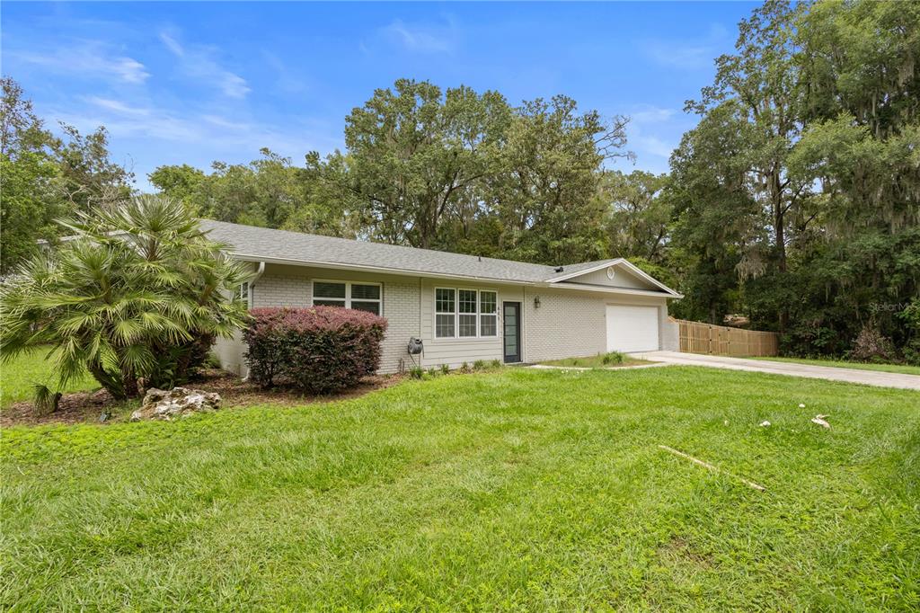A single-story brick house with a white garage and a large front lawn — 805 NW 40TH TERRACE, GAINESVILLE, FL