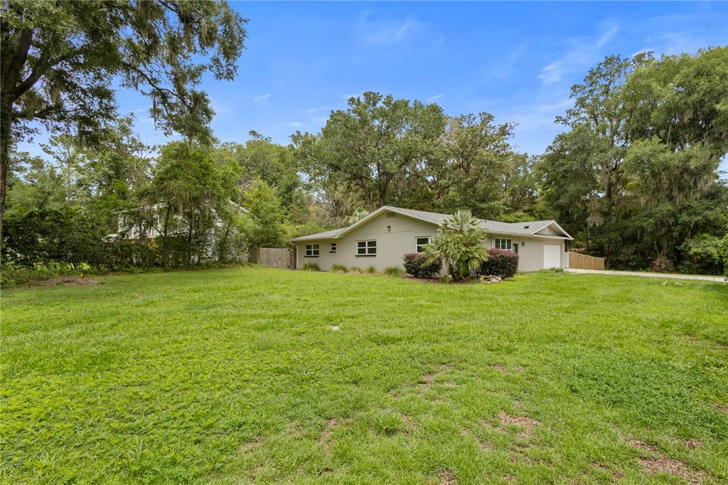 A single-story house with a light-colored exterior sits on a large, grassy lot — 805 NW 40TH TERRACE, GAINESVILLE, FL
