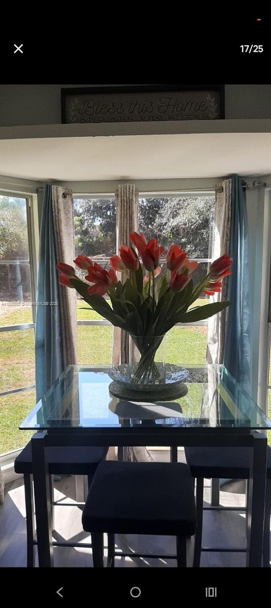 A glass-topped dining table with a floral centerpiece sits in a sunlit breakfast nook — 3809 palazzo, Sebring FL 33872, SEBRING, FL
