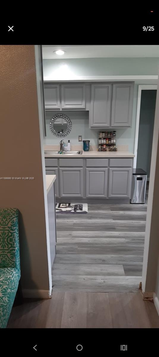 A kitchen features gray cabinets, light countertops, and wood-look flooring viewed through a doorway — 3809 palazzo, Sebring FL 33872, SEBRING, FL