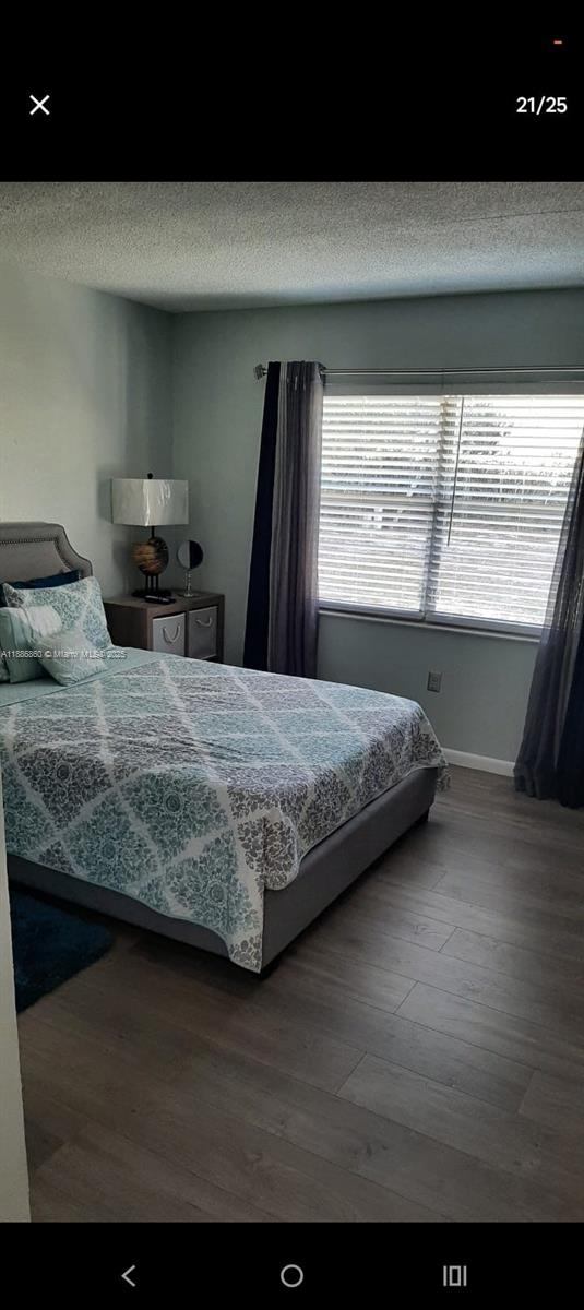 A bedroom features a gray upholstered bed, wood-look flooring, and a window with dark curtains — 3809 palazzo, Sebring FL 33872, SEBRING, FL