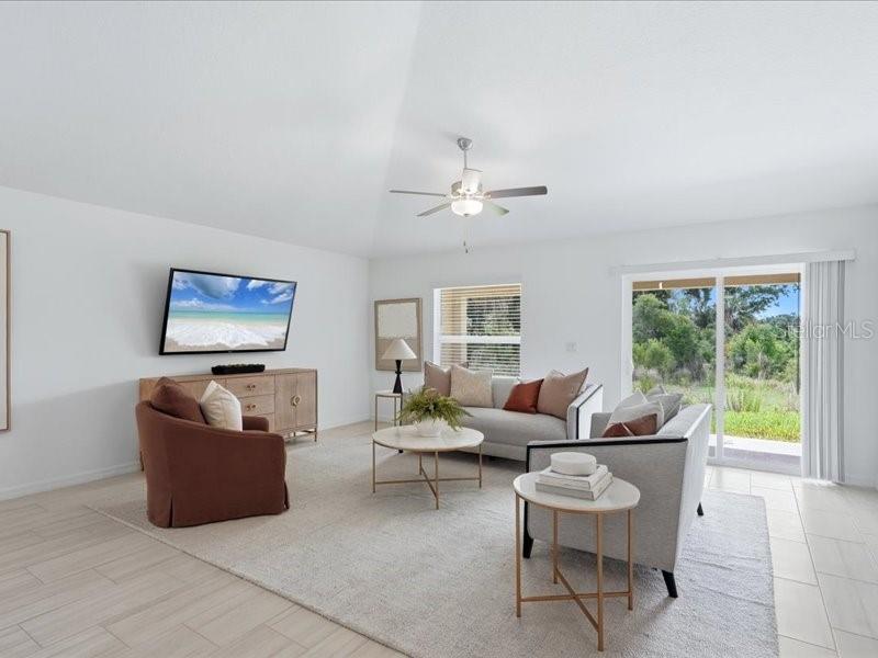 A living room with a vaulted ceiling, light tile floors, and a sliding glass door — 12032 BLUE DIAMOND TRAIL, PARRISH, FL