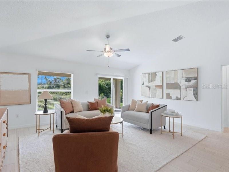 A bright living room features light-colored furniture, a ceiling fan, and abstract wall art — 12032 BLUE DIAMOND TRAIL, PARRISH, FL