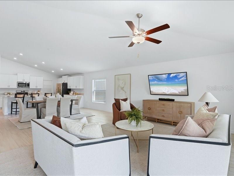 An open-concept living room and kitchen feature white cabinetry, a ceiling fan, and neutral furniture — 12032 BLUE DIAMOND TRAIL, PARRISH, FL