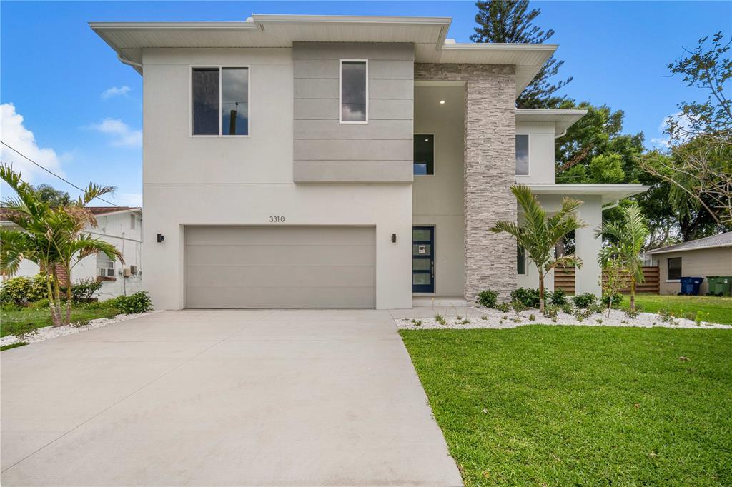 A two-story modern house features a concrete driveway, a two-car garage, and stone veneer accents — 3310 W ROGERS AVENUE, TAMPA, FL