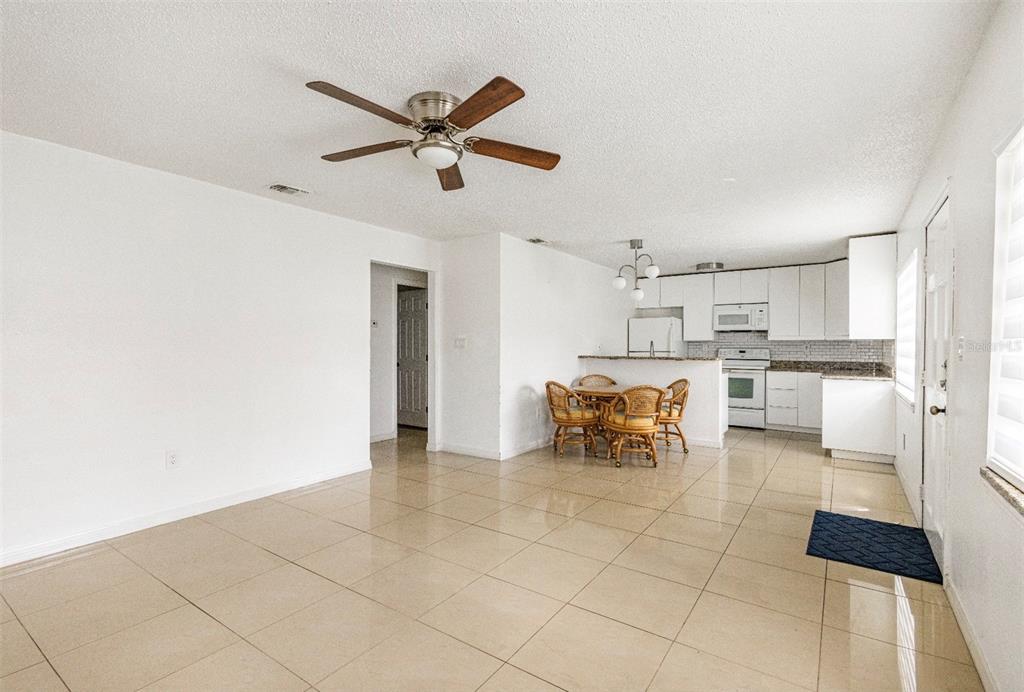 An open-concept kitchen and dining area with tile floors, white cabinets, and a ceiling fan — 1831 BOUGH AVENUE UNIT 1, CLEARWATER, FL