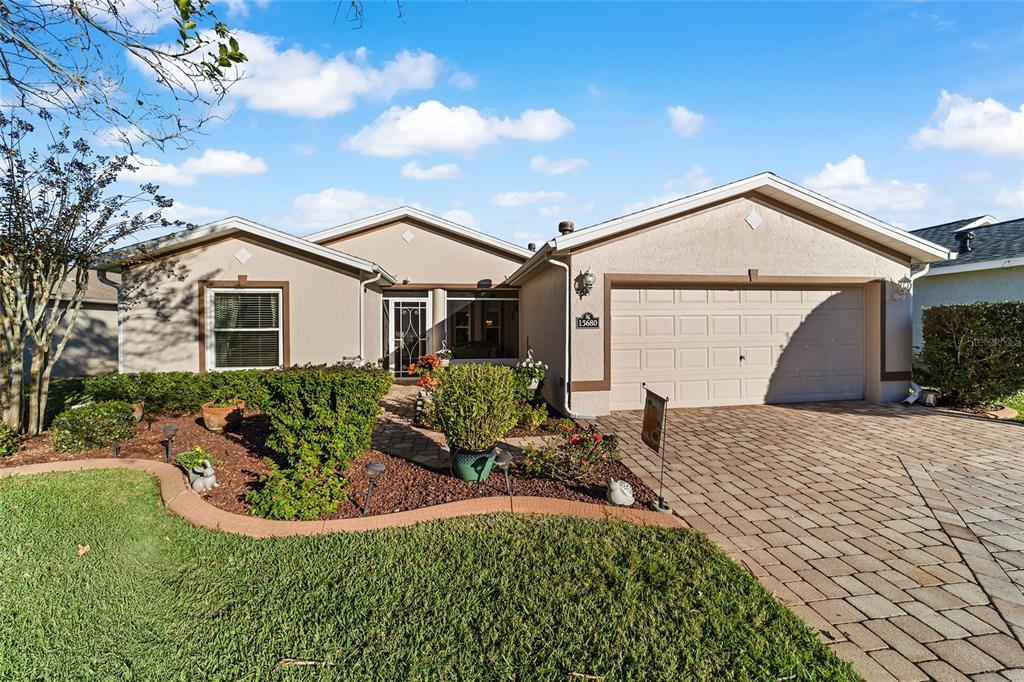 A single-story house with a beige stucco exterior, a paved driveway, and a landscaped front yard — 15680 SW 13TH CIRCLE, OCALA, FL