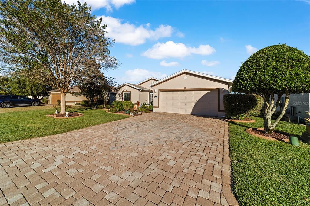 A single-story house with a beige exterior, a paved driveway, and a two-car garage — 15680 SW 13TH CIRCLE, OCALA, FL