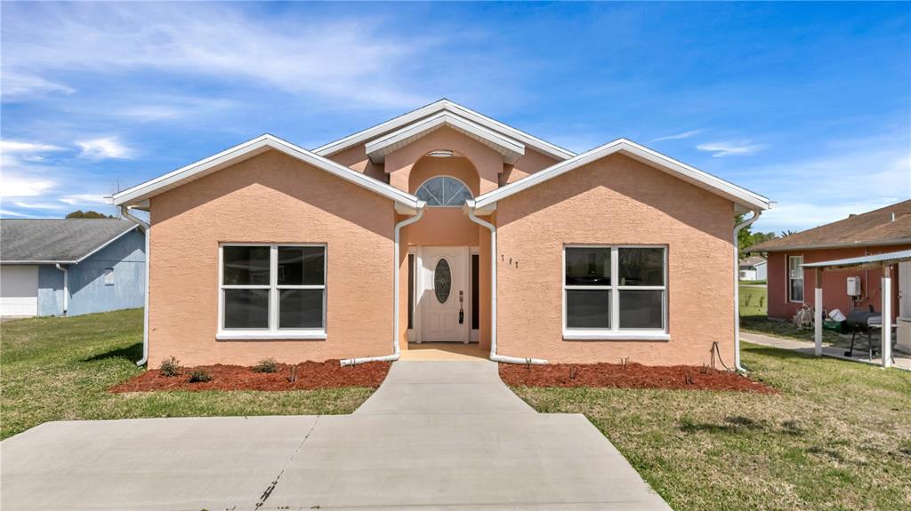 A peach-colored single-story house with a concrete walkway and a central arched entryway — 707 HAMILTON STREET, NEW SMYRNA BEACH, FL