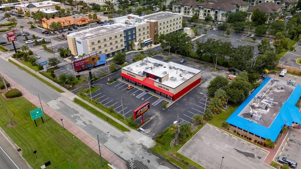 An aerial view shows a commercial building with a red facade and a parking lot — 6071 W IRLO BRONSON MEMORIAL HIGHWAY, KISSIMMEE, FL