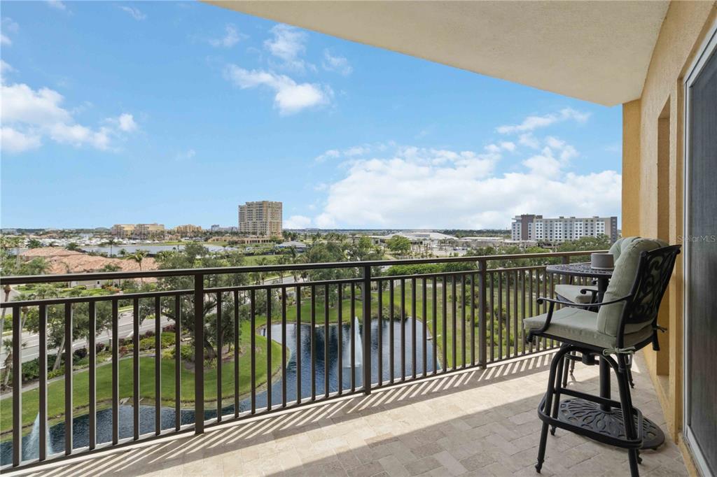 A balcony with a metal railing overlooks a pond, fountain, and distant buildings — 501 HABEN BOULEVARD UNIT 605, PALMETTO, FL