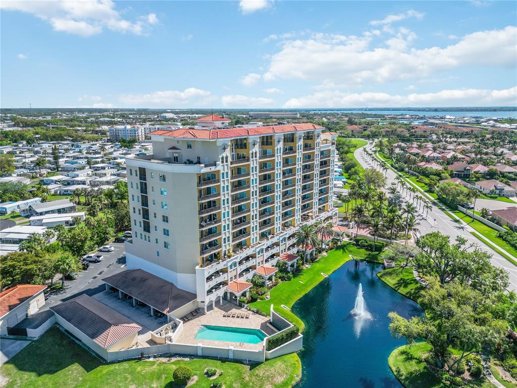 An aerial view shows a multi-story apartment building with a pool and fountain — 501 HABEN BOULEVARD UNIT 605, PALMETTO, FL