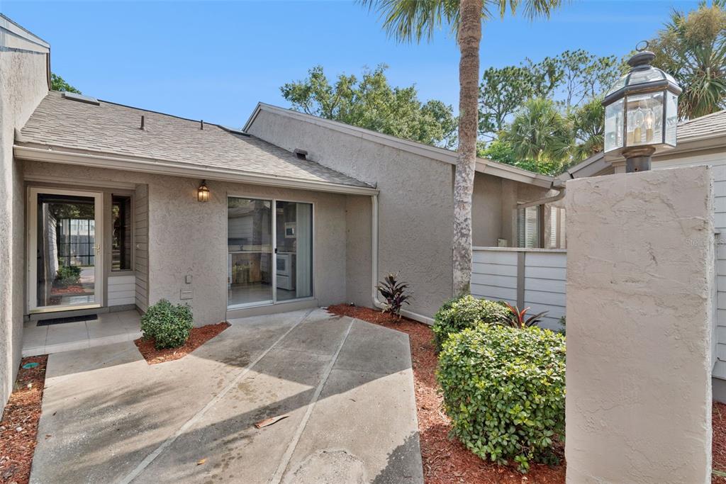 A concrete walkway leads to the front entrance and sliding glass doors of a stucco home — 419 WARRENTON ROAD UNIT 419, WINTER PARK, FL