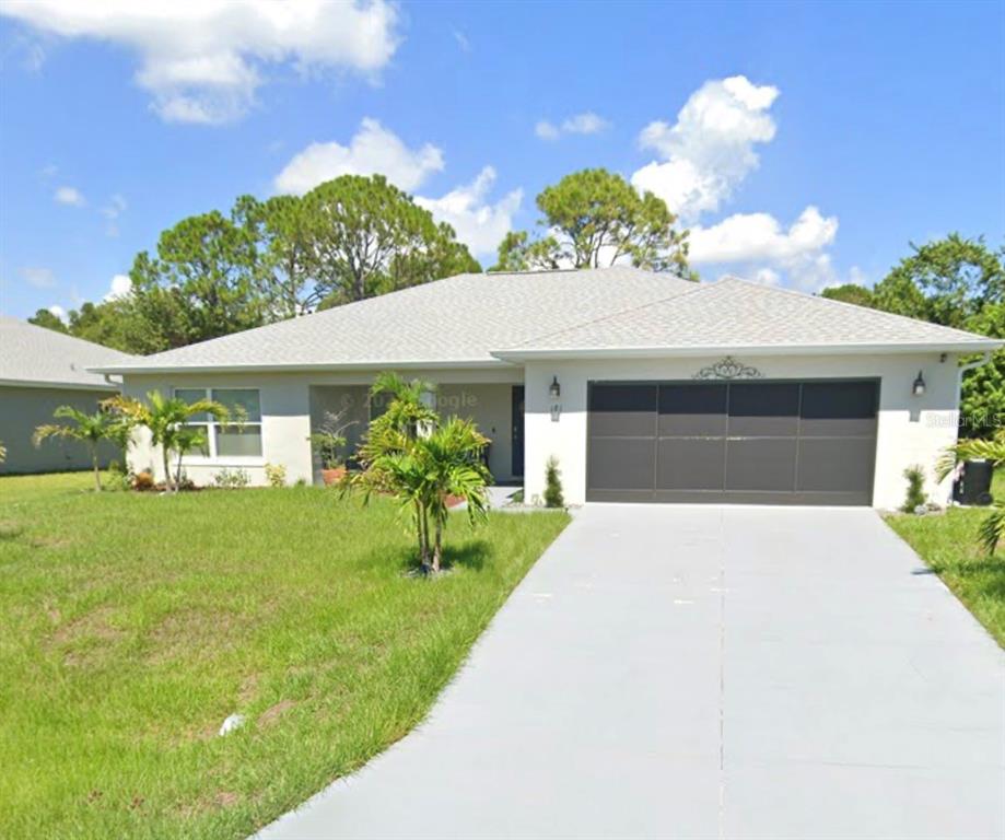 A single-story house with a gray garage door, a concrete driveway, and a grassy lawn — 181 DISTRICT STREET SE, PALM BAY, FL