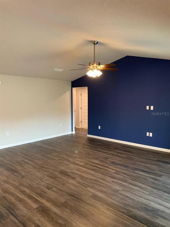 A room with dark wood-look flooring, a vaulted ceiling, a ceiling fan, and a blue accent wall — 181 DISTRICT STREET SE, PALM BAY, FL
