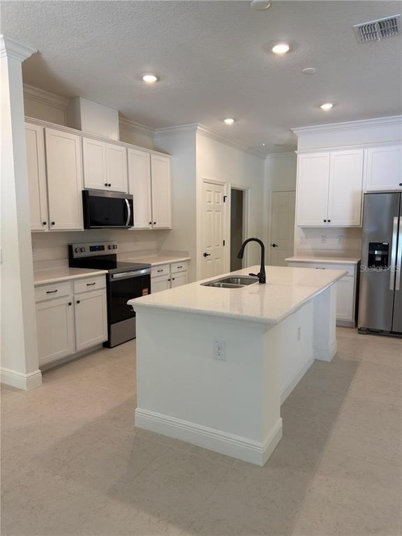 A kitchen features white cabinets, a central island with a sink, and stainless steel appliances — 8925 N GOLFVIEW DRIVE, CITRUS SPRINGS, FL