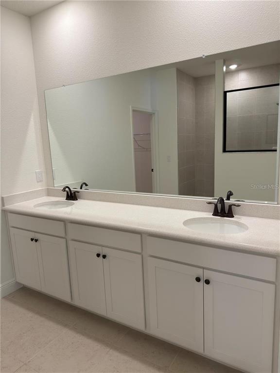 A bathroom vanity features white cabinets, a light-colored countertop, dual sinks, and a large mirror — 8925 N GOLFVIEW DRIVE, CITRUS SPRINGS, FL