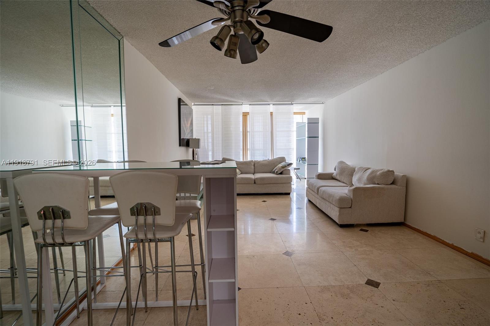 A living room features a breakfast bar, tile flooring, and two beige sofas — 701 Three Islands Blvd # 506, Hallandale Beach FL 33009, HALLANDALE BEACH, FL