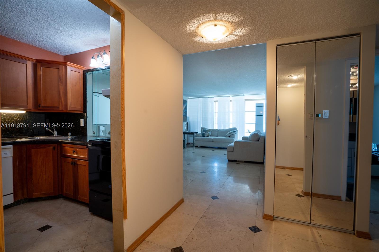 A view from a tiled hallway looking into a kitchen and a living room — 701 Three Islands Blvd # 506, Hallandale Beach FL 33009, HALLANDALE BEACH, FL