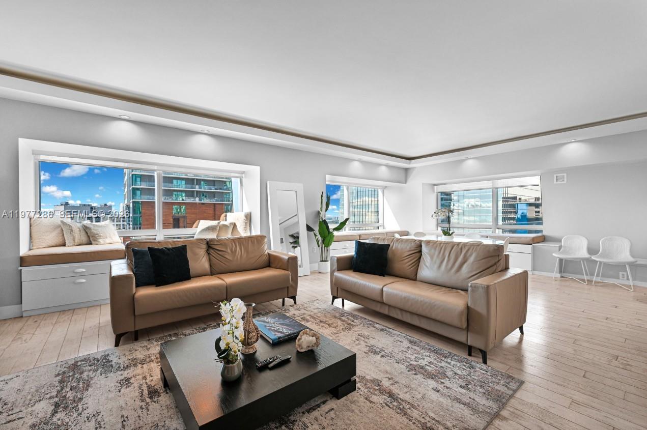 A bright living room features two leather sofas, a coffee table, and large windows — 1435 Brickell Ave # 3401, Miami FL 33131, MIAMI, FL