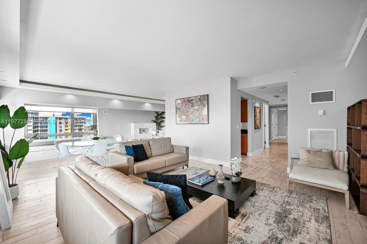A living room with light wood floors, two beige sofas, and a dining area — 1435 Brickell Ave # 3401, Miami FL 33131, MIAMI, FL