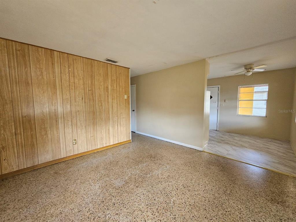 A living room features wood-paneled walls, terrazzo flooring, and an adjacent dining area — 1216 E MYRTLE STREET, LAKELAND, FL
