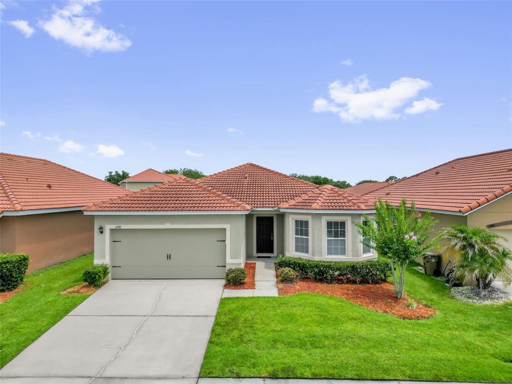 A single-story house with a two-car garage, tile roof, and a front lawn — 3078 SANGRIA STREET, KISSIMMEE, FL