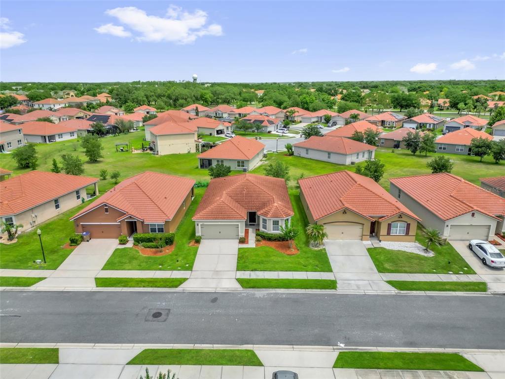 An aerial view of a suburban neighborhood featuring several single-story houses with red tile roofs — 3078 SANGRIA STREET, KISSIMMEE, FL