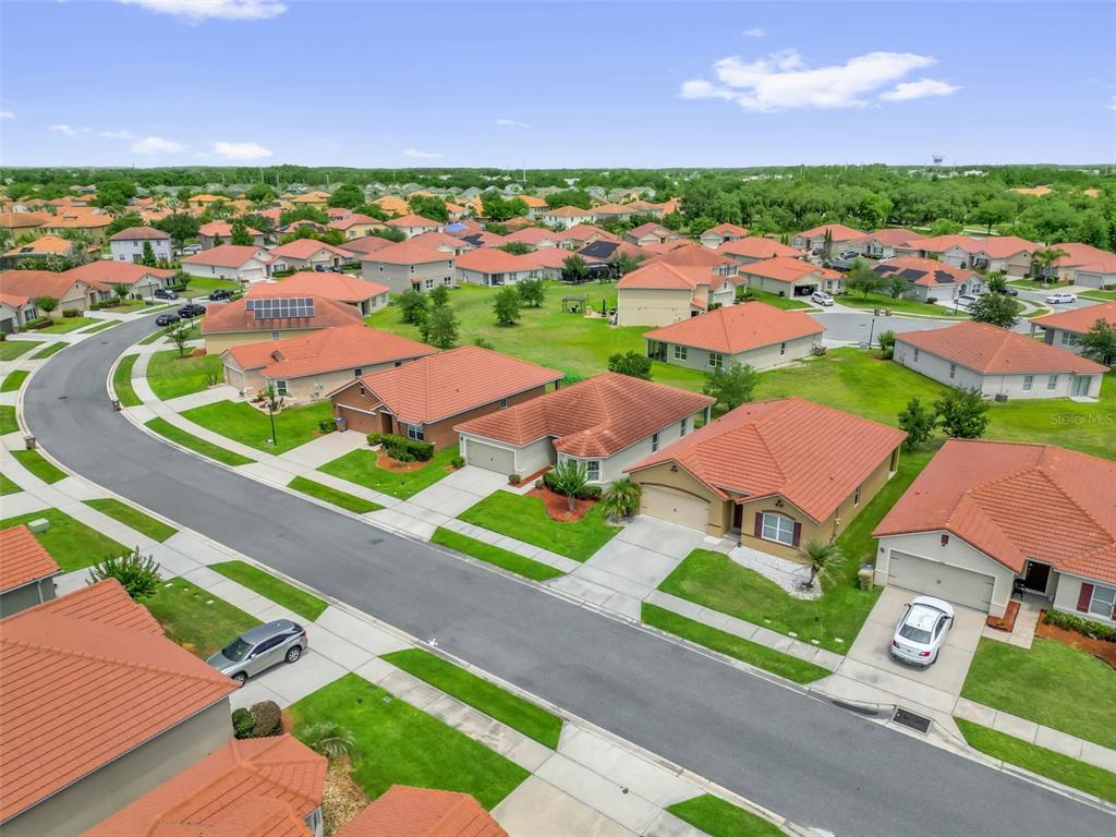 An aerial view shows a suburban neighborhood with many single-story houses featuring orange tile roofs — 3078 SANGRIA STREET, KISSIMMEE, FL