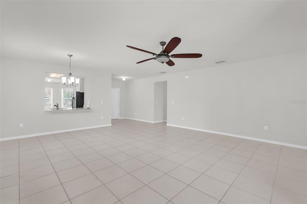 A dining area with tile floors, a wooden table, and a pass-through window to the kitchen — 3078 SANGRIA STREET, KISSIMMEE, FL
