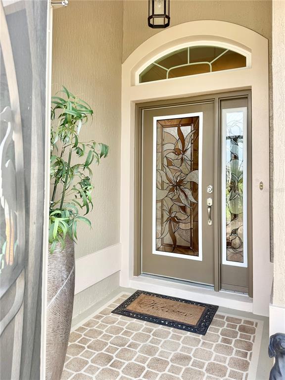 A front entryway features a tan door with decorative glass, a sidelight, and a transom window — 632 CORONACA COURT, THE VILLAGES, FL