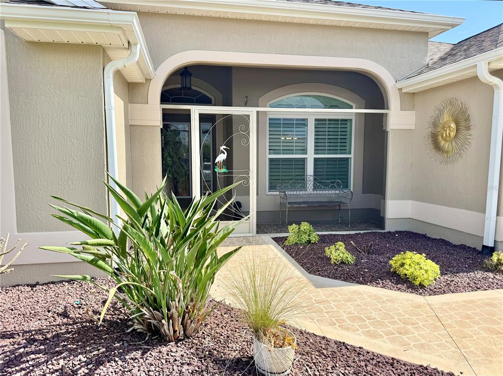 The exterior entrance features a covered porch, a screen door, and a landscaped front yard — 632 CORONACA COURT, THE VILLAGES, FL