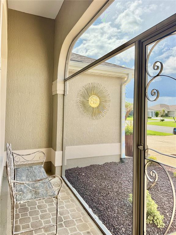 A screened-in porch features a metal bench, tiled flooring, and a decorative sun wall hanging — 632 CORONACA COURT, THE VILLAGES, FL