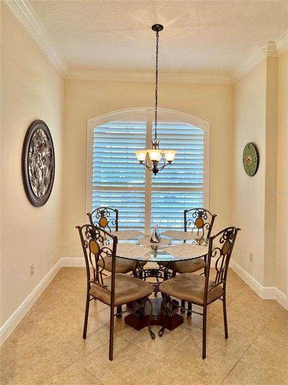 A dining area features a glass-topped table with four metal chairs under a chandelier — 632 CORONACA COURT, THE VILLAGES, FL