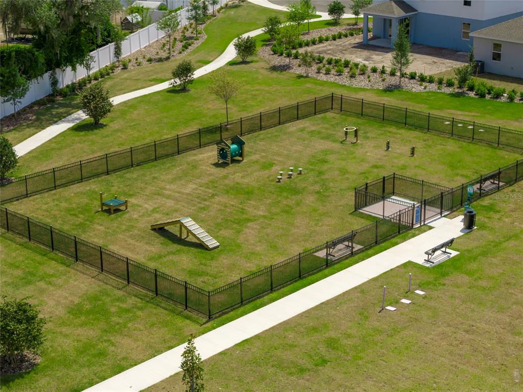 An aerial view of a fenced-in dog park featuring agility equipment and a paved walkway — 1950 IORIO STREET, ST CLOUD, FL