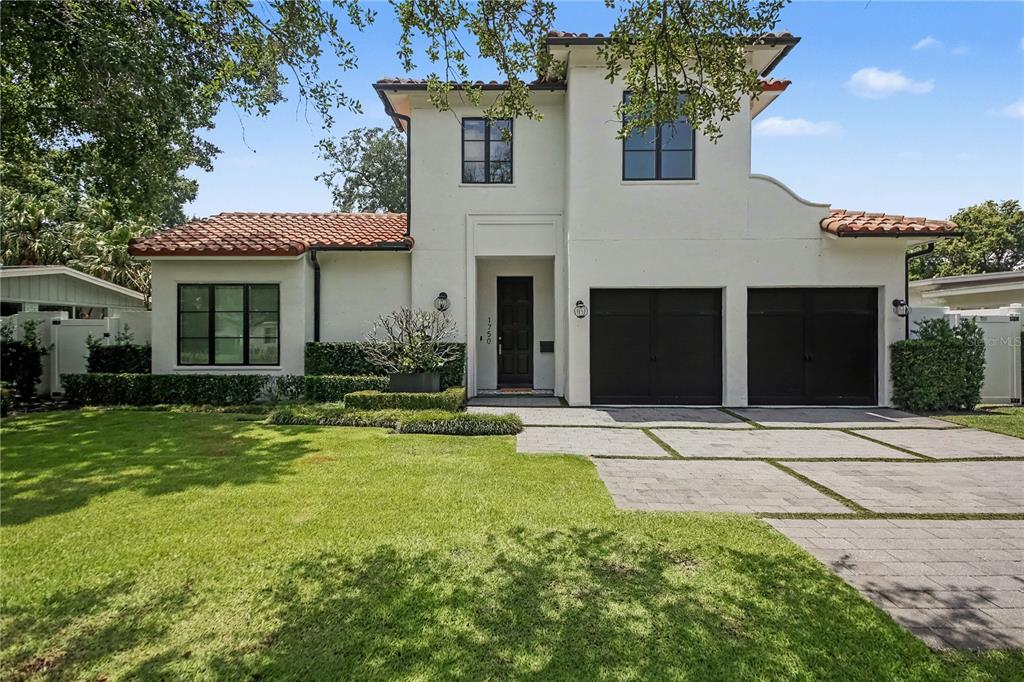 A two-story white stucco house features a tile roof, black garage doors, and a paved driveway — 1750 WALNUT AVENUE, WINTER PARK, FL