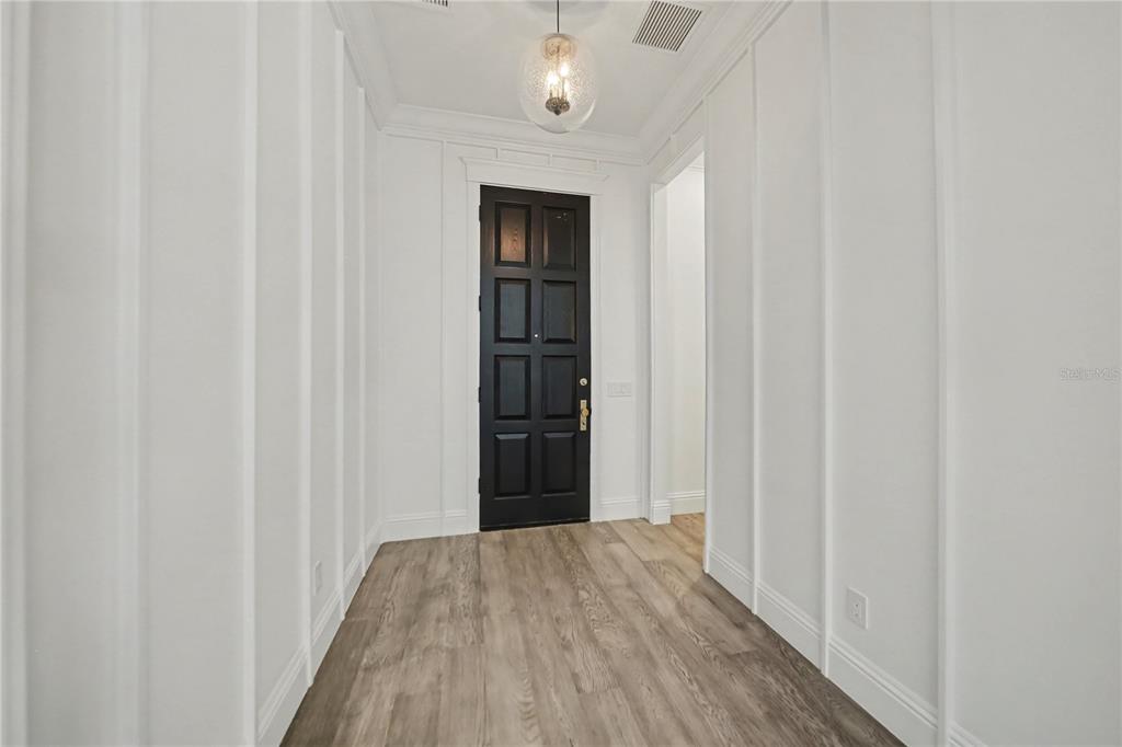 A hallway features white board-and-batten walls, wood-look flooring, and a dark paneled door — 1750 WALNUT AVENUE, WINTER PARK, FL