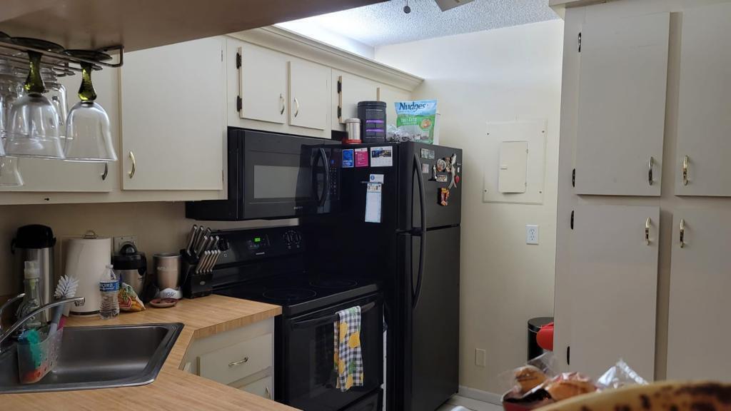 A kitchen features light-colored cabinets, black appliances, a stainless steel sink, and wood-look countertops — 203 Foxtail Drive # B3, FL 33415, FL