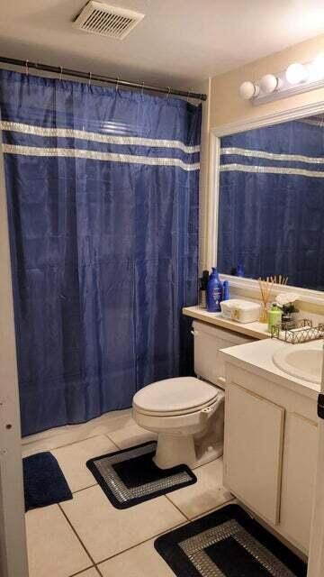 A bathroom features a blue shower curtain, a white toilet, and a vanity with mirror — 203 Foxtail Drive # B3, FL 33415, FL
