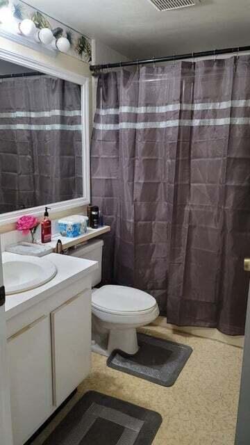 A bathroom features a white vanity, a toilet, and a dark gray shower curtain — 203 Foxtail Drive # B3, FL 33415, FL